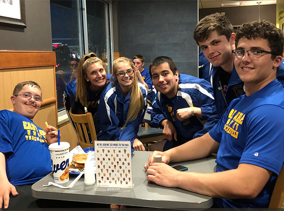 Six teammates in blue uniforms enjoy their visit to Culver’s.