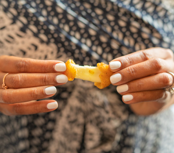 A close-up of a cheese curd being stretched apart