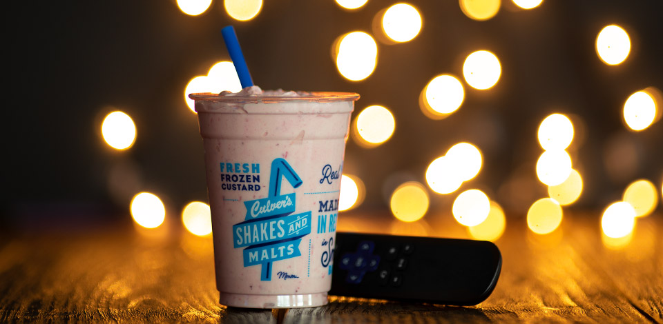 Shake next to a TV remote with holiday lights twinkling in the background.