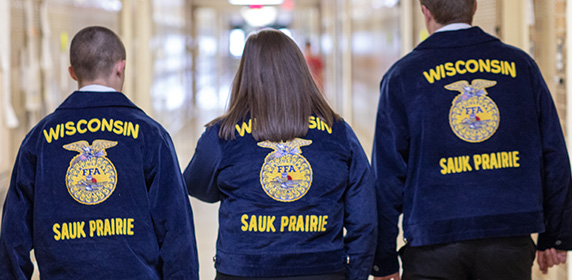 FFA students wearing FFA blue jackets, walking down a hallway