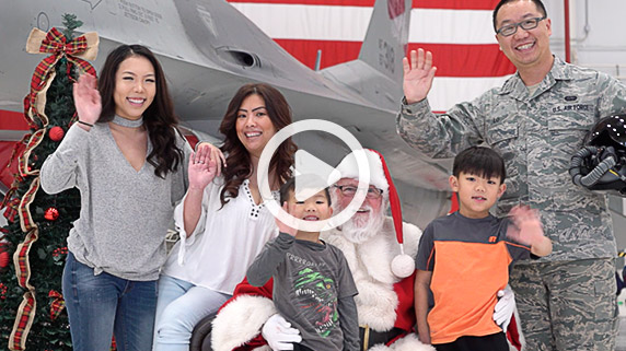 An airman with his family poses for a photo with Santa in front of an F-16 aircraft at the holiday party. Click to watch video.