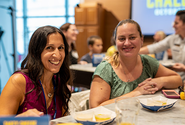 Two women, seated with empty cheese curd dishes, smile for the camera
